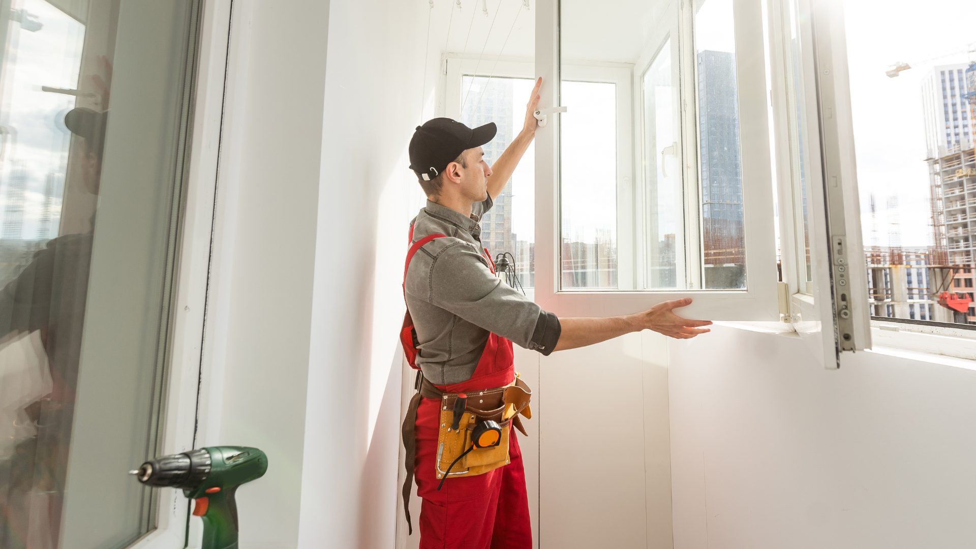 roof-restoration A professional in red coveralls installs a new window in a home.