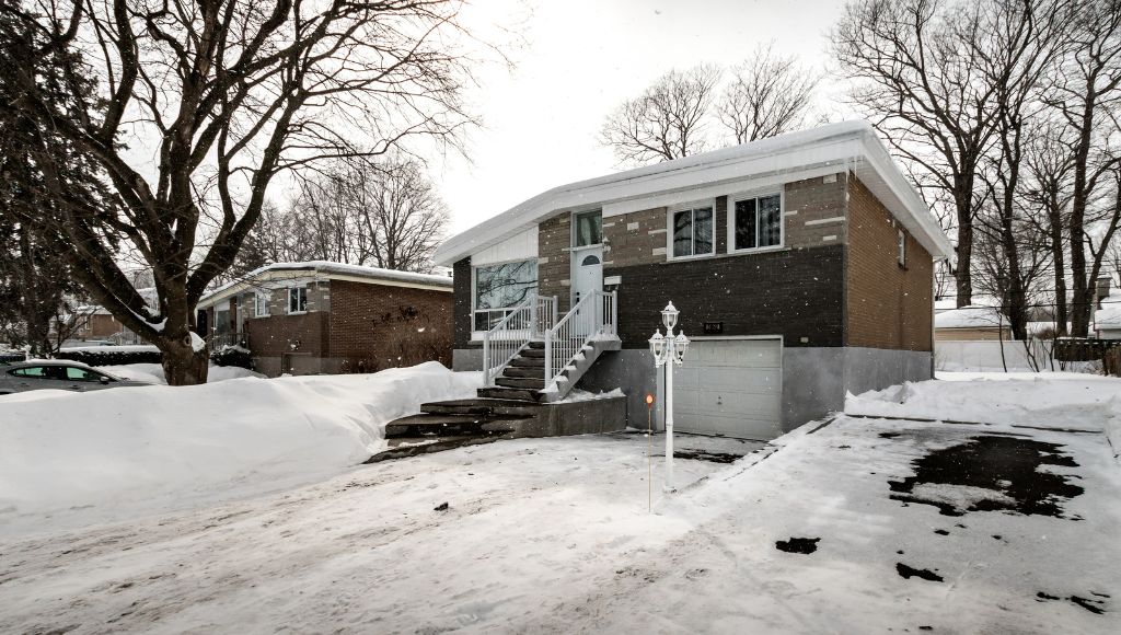 An older, 1970s-era home in a quiet suburban residential neighborhood in Central New York, blanketed in snow.