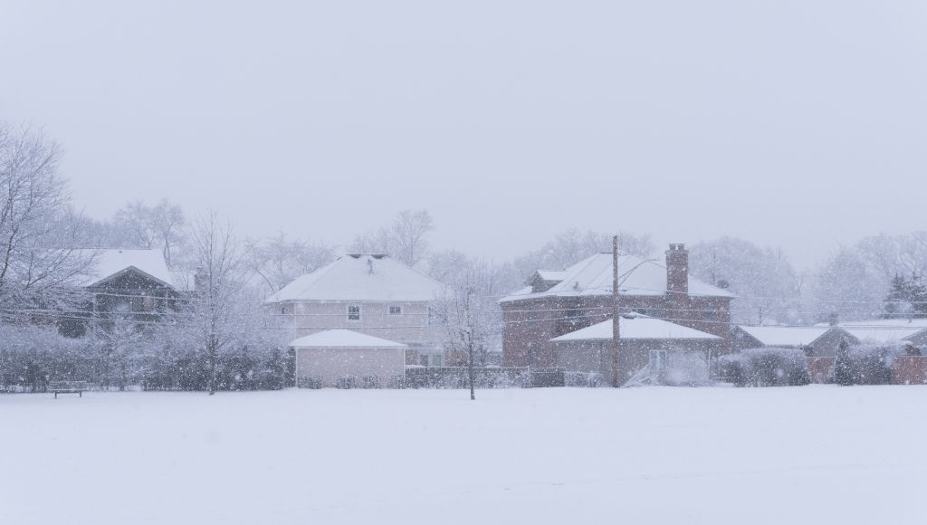 A suburban street in the middle of a heavy snowstorm.
