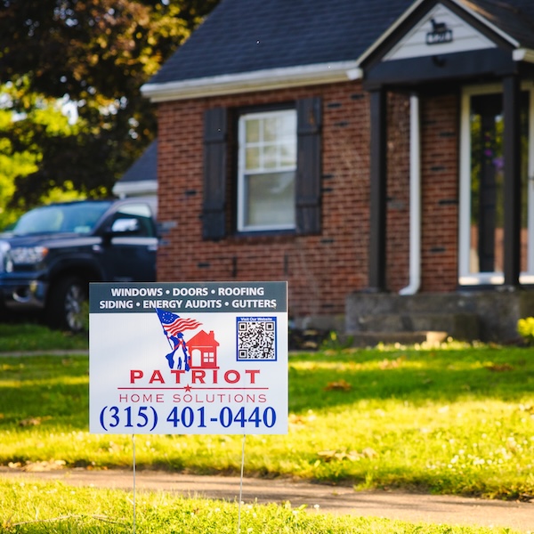 A well-kept brick residential home with a Patriot Homes sign on the front lawn