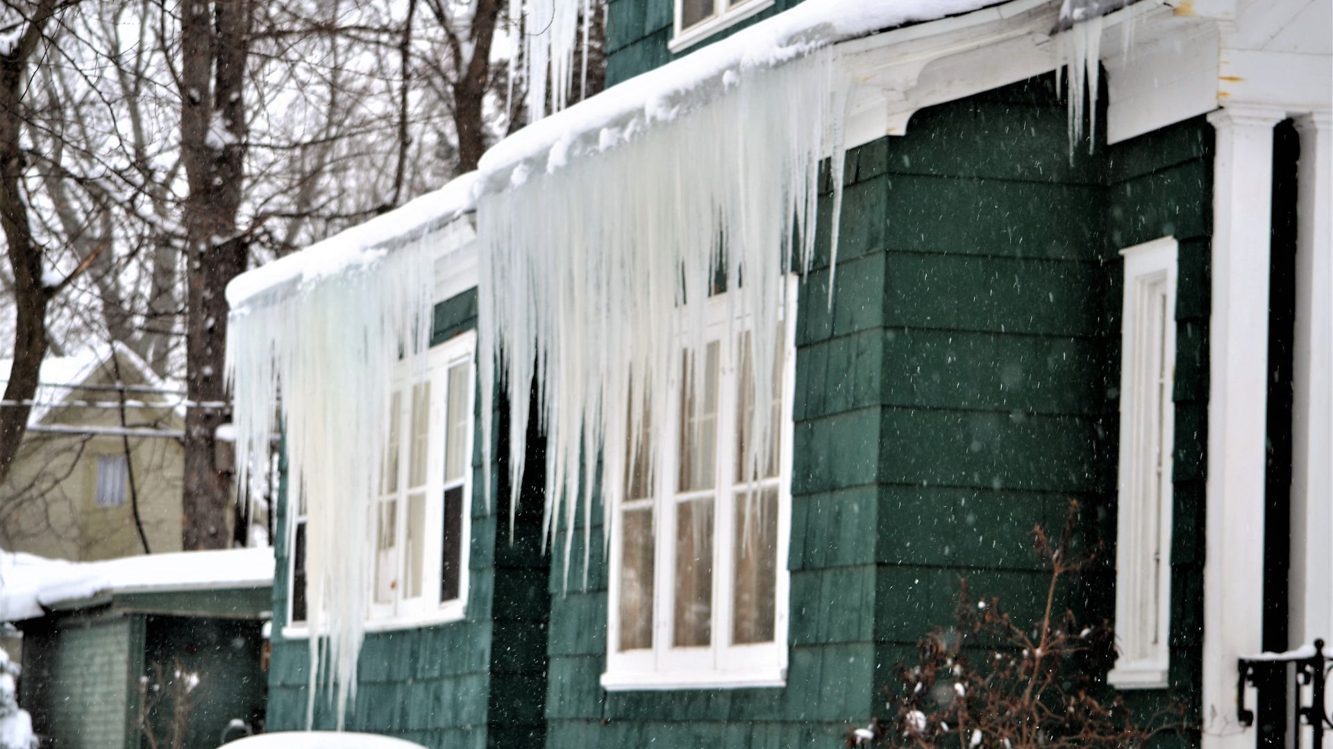 Large icicles hanging on a snow-filled roof.