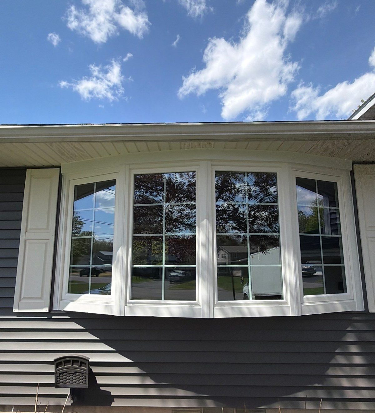 New white bow window with grids and white shutters on a 1960s North Syracuse home