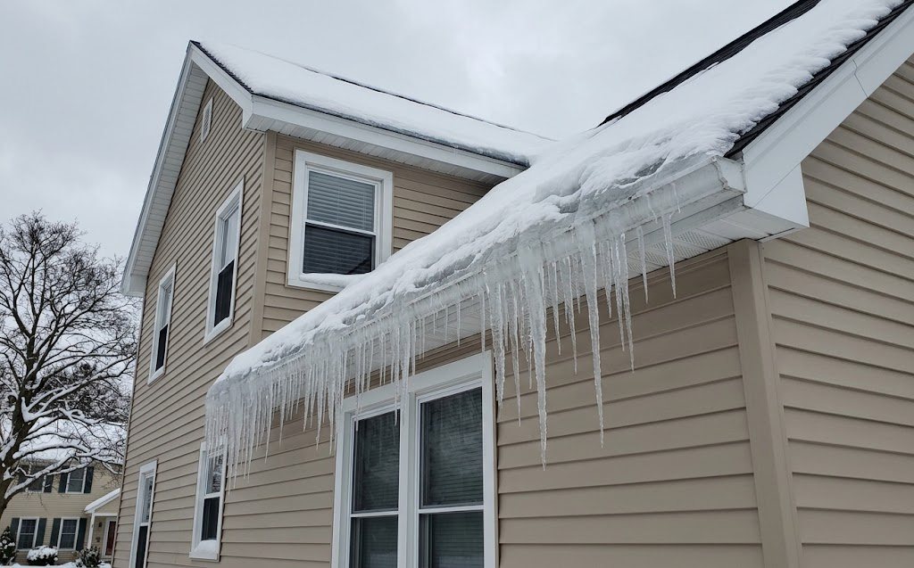 Ice dam and icicles along a house eave in winter