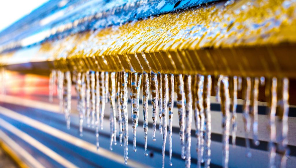 Close-up of icicles hanging from the eave of a roof on a sunny day.